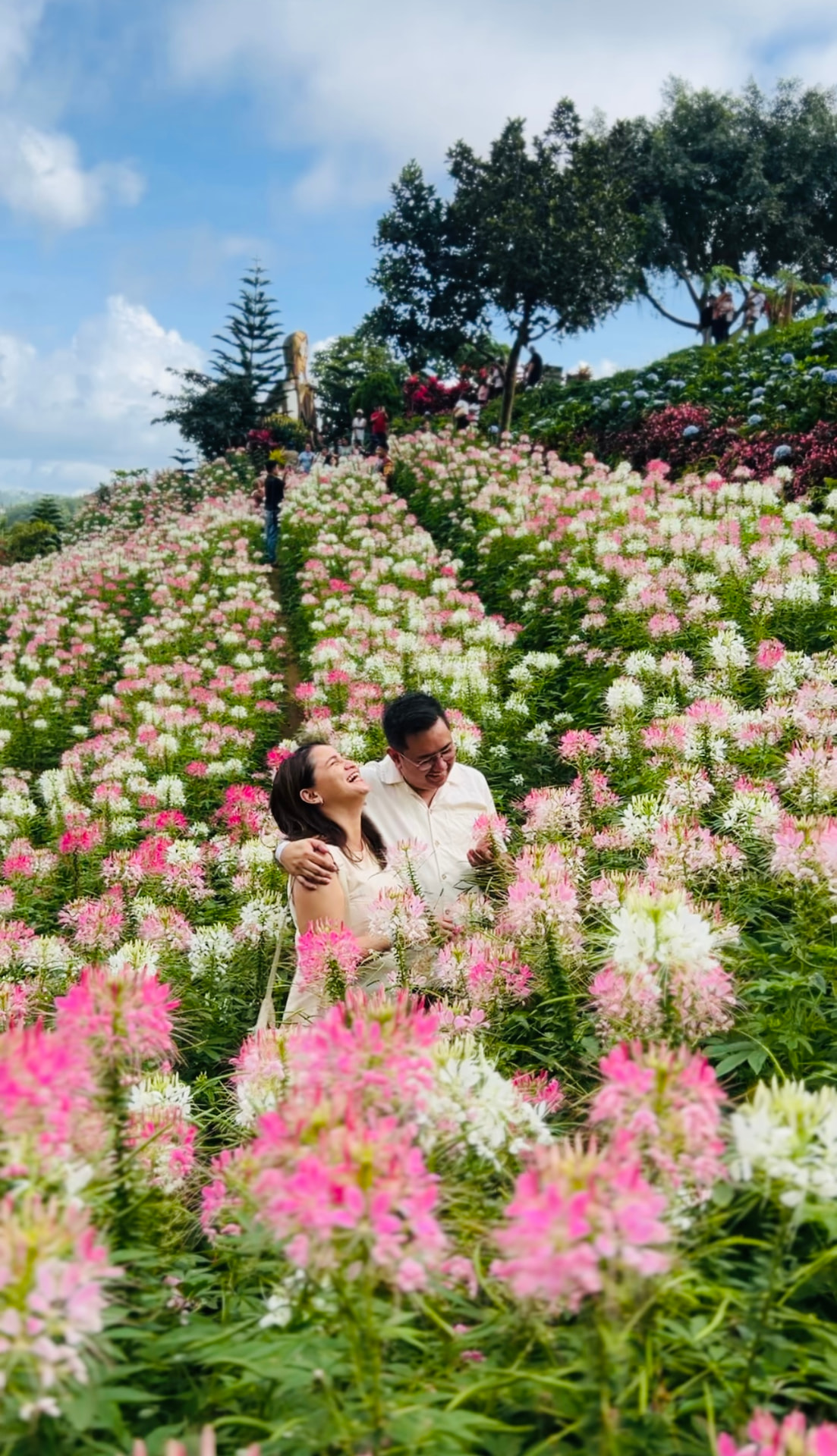 Rayray and Trina laughing together in a field of pink and white flowers